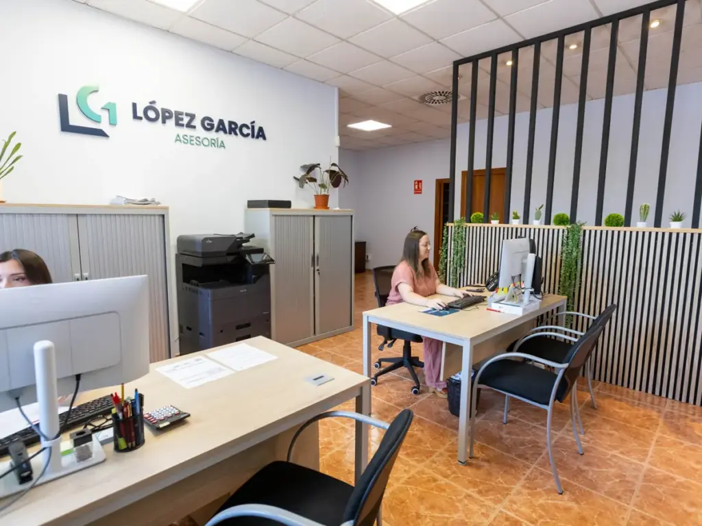 Interior de la oficina de Asesoría López García con el logotipo en la pared